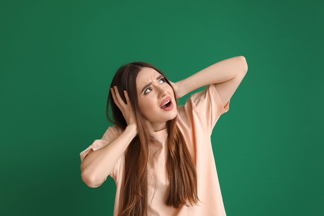 Junge Frau hält sich die Ohren zu, während sie zur Decke schaut