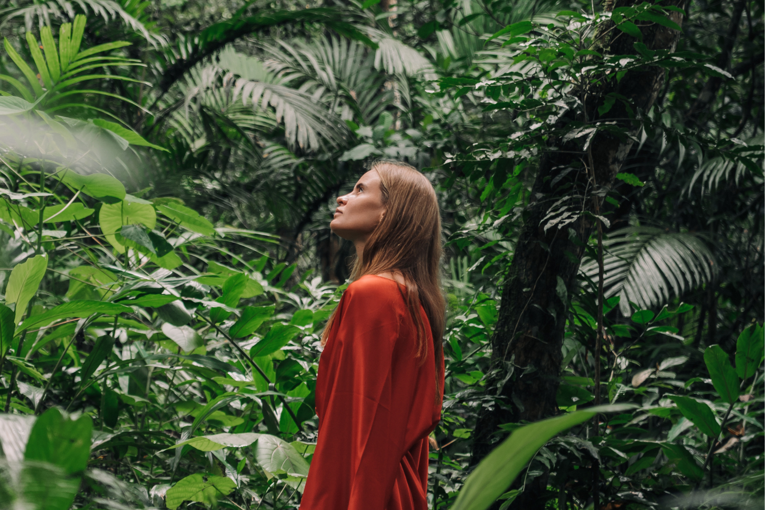 Seitenansicht einer Frau in rotem Kimono aus Baumwollsatin im Dschungel