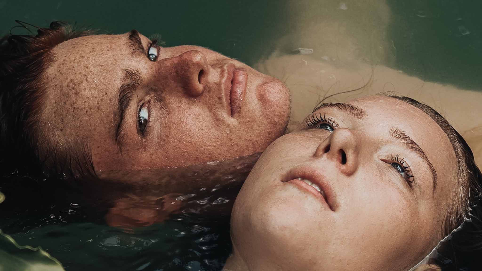 Junger Mann und junge Frau liegen im Wasser