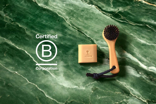 Nirvana Gesichtsseife und Metanoia Trockenbürste von Aninsu neben dem "Certified B Corporation"-Logo.