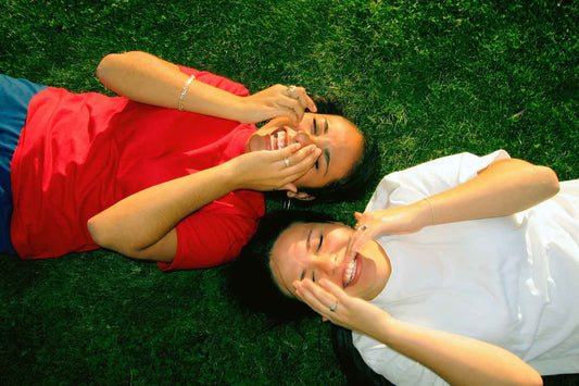 Lachyoga: zwei Frauen liegen auf einer Wiese und lachen ausgelassen