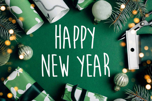 Schriftzug "Happy new year" auf grünem Hintergrund mit festlicher Dekoration
