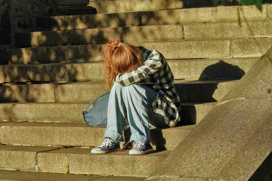 Verletzlichkeit in der Öffentlichkeit: junge Frau traurig auf Treppe sitzend